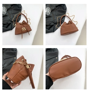 Detail view of brown bucket bag showing drawstring closure and golden H-shaped hardware