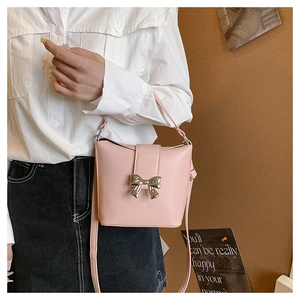 Detail of light pink bucket bag with gold butterfly bow and adjustable strap