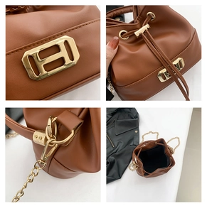Detail view of brown leather bucket bag with gold H-buckle, drawstring and chain strap