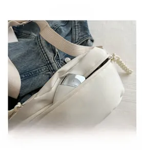 Close-up detail of white nylon crossbody sling bag with woven strap and blue denim jacket