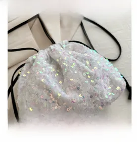 Détail de fermeture à cordon et paillettes irisées sur ce sac seau blanc chic