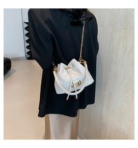 Detail of white bucket bag with gold H hardware and chain strap on black blazer