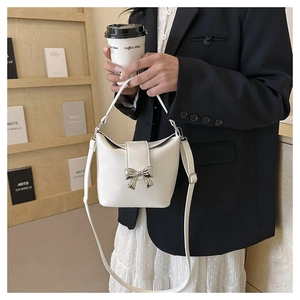 Close-up of elegant white leather handbag featuring a silver butterfly bow accent