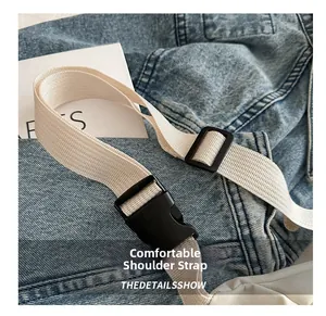 Detail of adjustable beige woven shoulder strap with black plastic buckle for chest bag