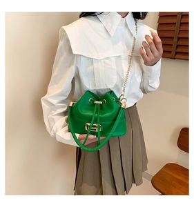 Detail of green drawstring bucket bag with gold H buckle and fine chain strap