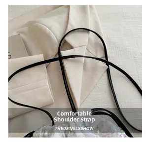 Détail de la bandoulière confortable en cuir noir sur un sac seau à paillettes colorées