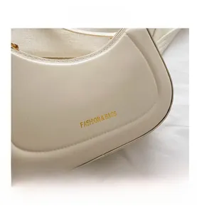 Detail of creamy white crescent shoulder bag with golden FASHION & BAGS text