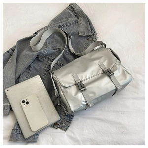 Close-up of silver metallic crossbody bag with dual buckle straps and textured fabric