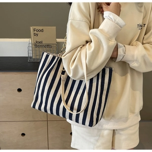 Detailed close-up of blue striped tote bag with elegant golden chain and leather strap