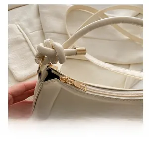 Detailed view of the gold zipper closure and logo embossing on the beige handbag