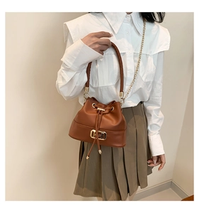 Close-up of brown leather bucket bag featuring a drawstring closure and gold hardware details