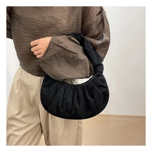 Détail du sac croissant plissé en velours côtelé noir porté par un mannequin sur l'épaule