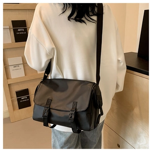 Detailed view of black nylon messenger bag featuring dual buckle closure on shoulder strap