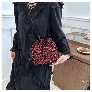 Détail du sac seau à paillettes rouges avec cordon en cuir noir et silhouette élégante