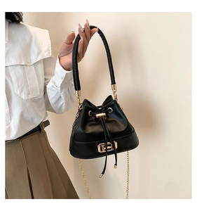 Close-up of black leather bucket bag with gold chain strap and drawstring closure