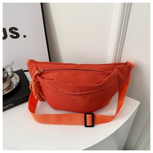 Detail view of the orange canvas crossbody bag featuring a woven zipper pull and nylon strap