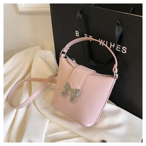 Detail of light pink leather bag featuring a silver butterfly buckle and top handle