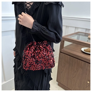 Gros plan d'un sac seau à paillettes rouges avec cordon et fine bandoulière noire