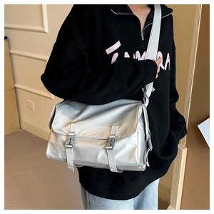 Detail of silver messenger bag with durable plastic buckles and glossy nylon fabric