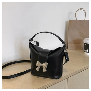 Close-up of black bucket bag with silver butterfly bow on a wooden surface