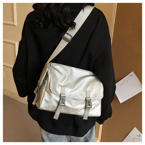 Silver messenger bag with double buckles and side pockets shown in a modern interior setting