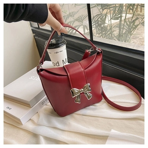 Detailed view of dark red leather handbag featuring a silver butterfly clasp and strap