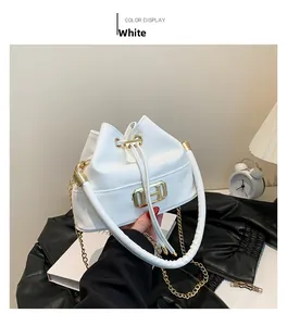 Close-up of white leather bucket bag featuring a gold H-shaped buckle and metal chain strap