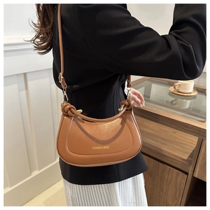 Detail view of brown faux leather crescent bag with unique knotted handle design