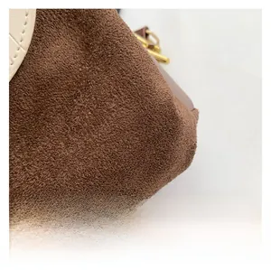 Close-up of brown suede and white quilted leather contrast with gold metal buckle