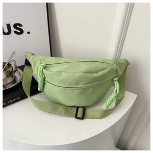 Detail of light green nylon waist bag with dual zippers and adjustable woven strap