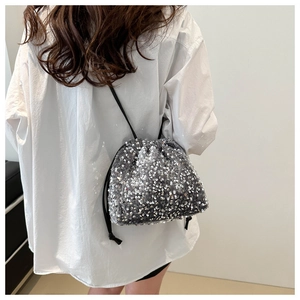 Détail d'un sac seau à paillettes argentées avec cordons portés par un mannequin