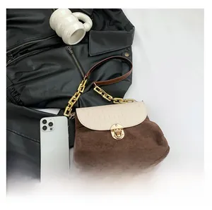Detail view of brown suede shoulder bag with off-white crocodile texture and golden chain