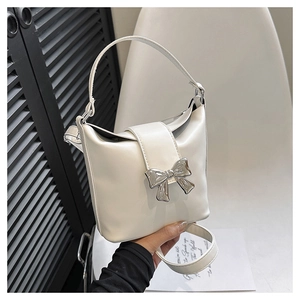Detail of cream white bucket bag with silver metal bow and adjustable shoulder strap