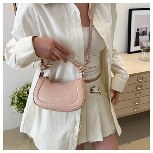 Detail of pink leather crescent bag with golden FASHION & BAGS text and top knot handle