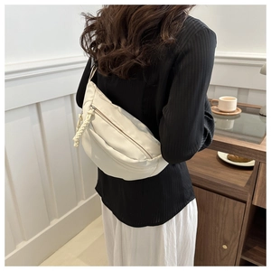 Detail of minimalist cream-colored crossbody waist bag with woven rope zipper pull decoration