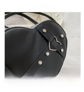 Detailaufnahme der schwarzen herzförmigen Handtasche mit Nieten und Metallverschluss