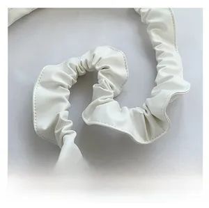Detail of the white pleated shoulder strap with fine stitching on quality leather bag