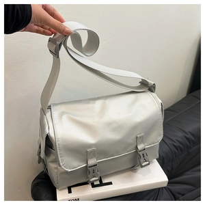 Detail of silver messenger bag showing flap cover and two dark grey plastic buckles