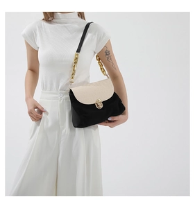 Detailed view of crocodile pattern flap and golden twist lock on stylish crossbody bag
