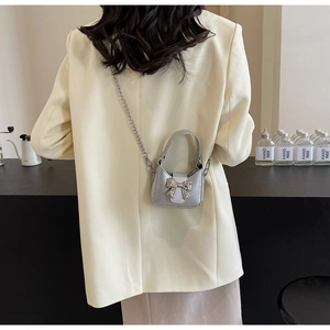 Silver mini bow handbag with metallic chain strap shown against a chic fashion backdrop
