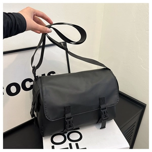 Detail of black crossbody messenger bag featuring durable fabric and dual buckle closure