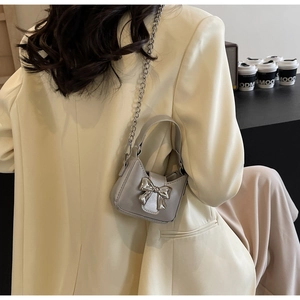 Detailed view of silver bow-knot mini crossbody bag with metal chain strap on model