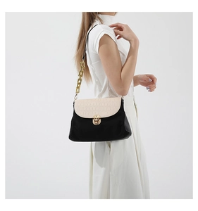 Detail of the crocodile pattern on the beige flap and golden twist lock of the handbag