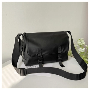 Close-up of black matte nylon messenger bag with double buckles and wide shoulder strap