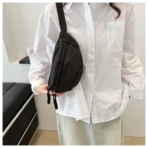 Close-up of black minimalist crossbody chest bag with adjustable strap and textured zipper