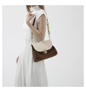 Close-up of golden twist lock and chain detail on stylish patchwork shoulder bag