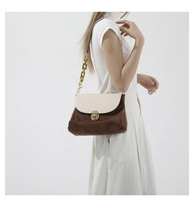 Detailed side view of woman wearing patchwork shoulder bag with gold chain strap