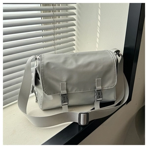 Detail of light gray messenger bag featuring matte waterproof fabric and plastic buckles