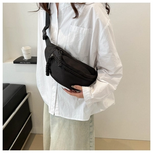 Close-up of minimalist black canvas chest bag with woven rope zippers and plastic buckle