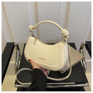 Detail of cream white hobo bag with knotted handle and golden logo on smooth faux leather